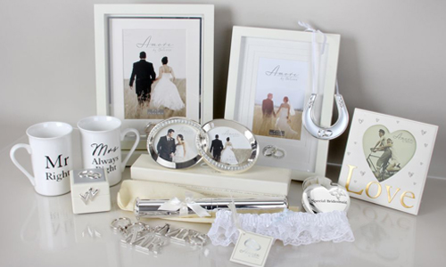 An arrangement of wedding gifts including mr and mrs mugs, photo frames and a silver horseshoe.